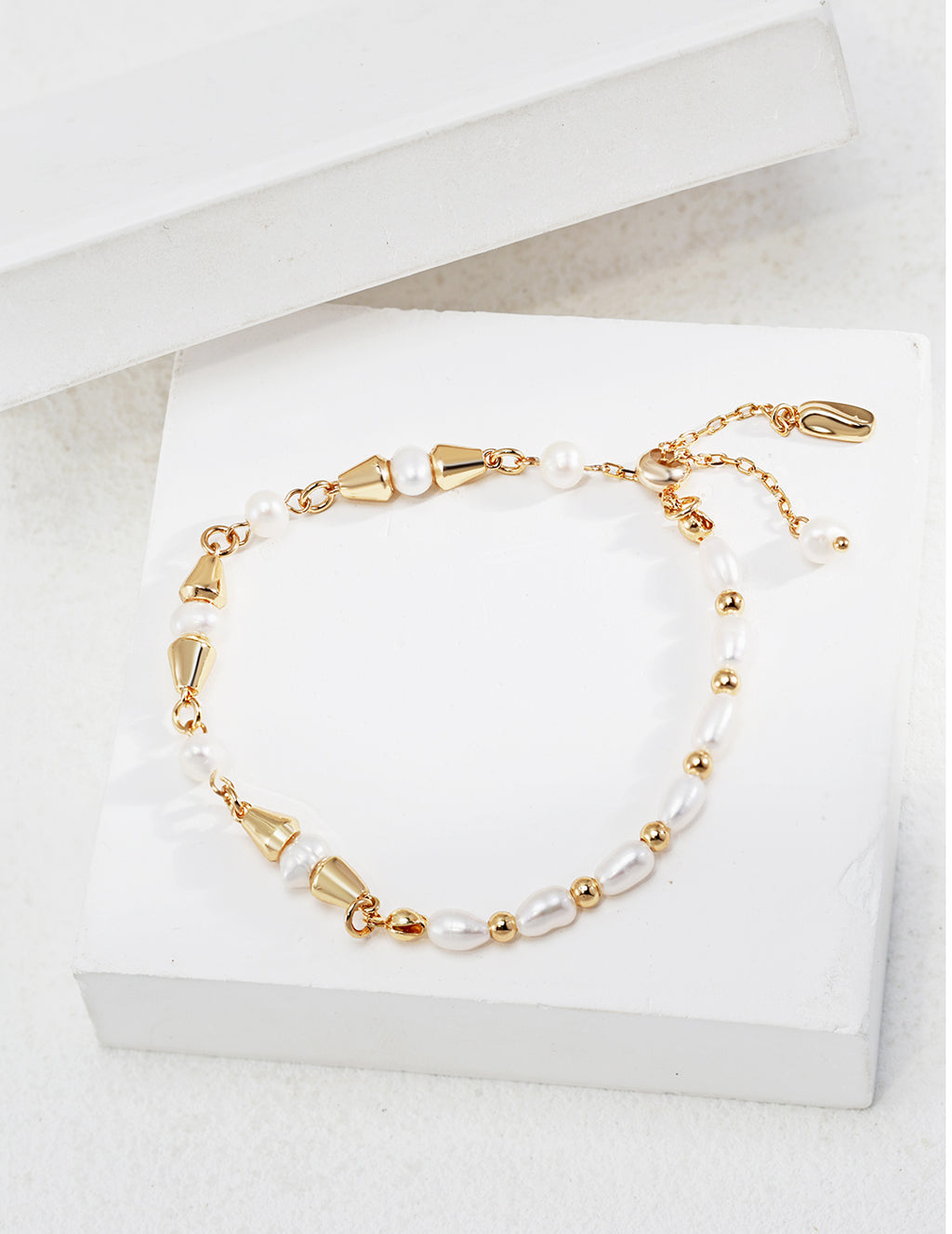Vintage-gold sterling silver bracelet with natural pearls, polished beads and tapered metal elements arranged asymmetrically.