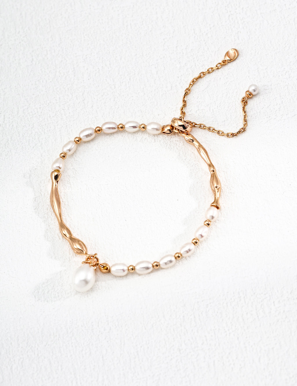 Vintage-gold sterling silver bracelet with elongated natural pearls, sculptural metal sections and a hanging drop-shaped pearl.