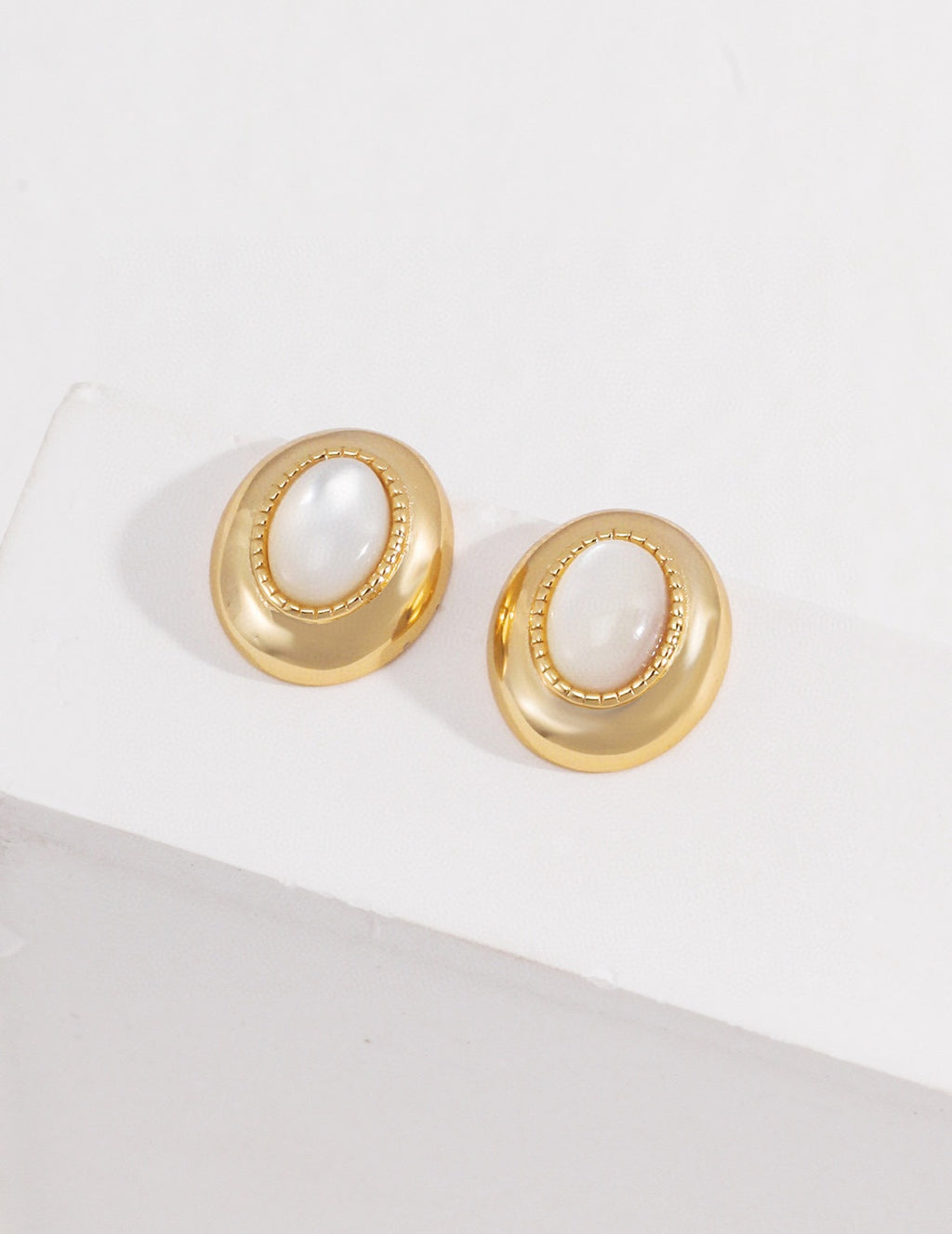 Vintage-gold sterling silver earrings with oval mother-of-pearl centers, textured borders and softly irregular metal surrounds.