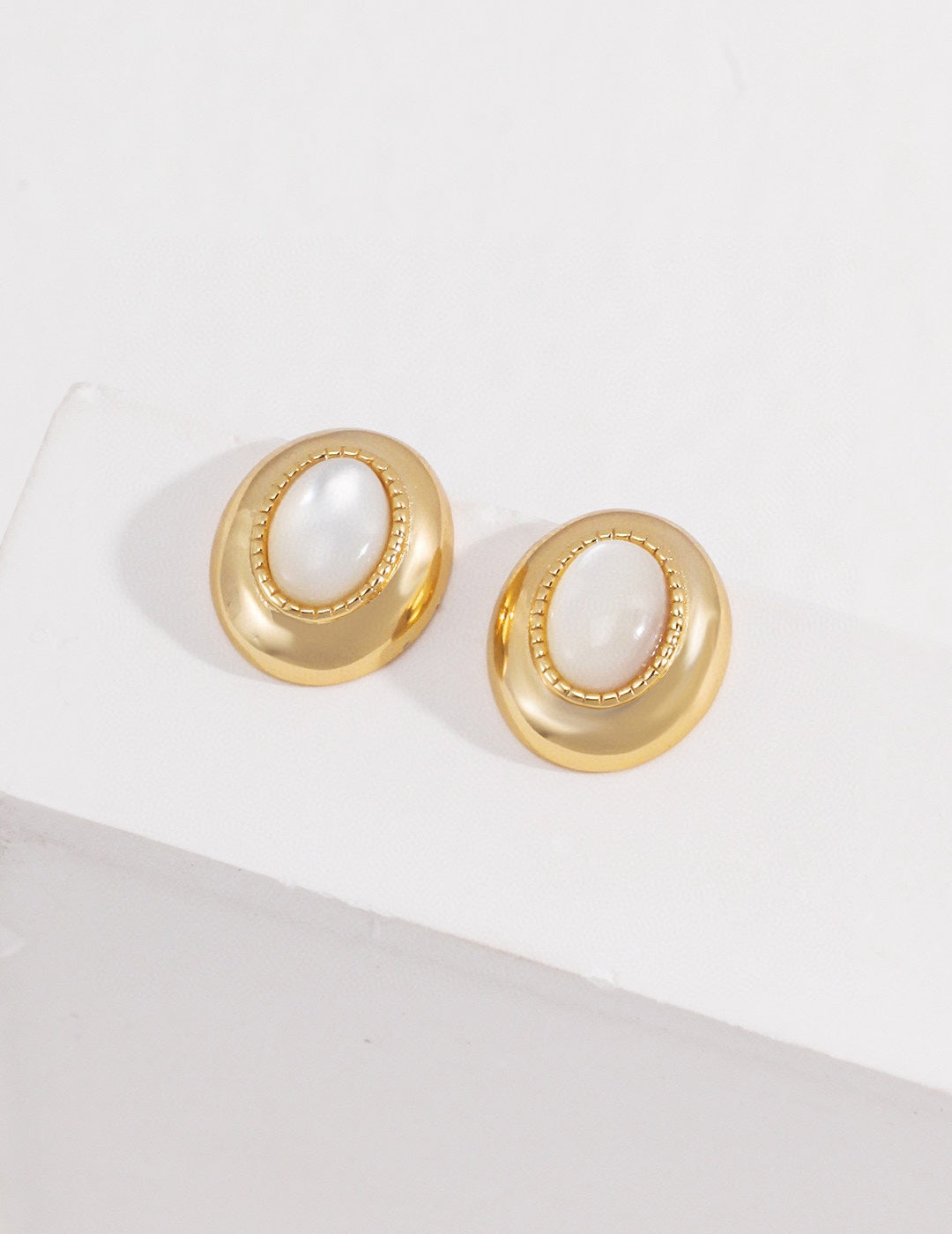 Vintage-gold sterling silver earrings with oval mother-of-pearl centers, textured borders and softly irregular metal surrounds.
