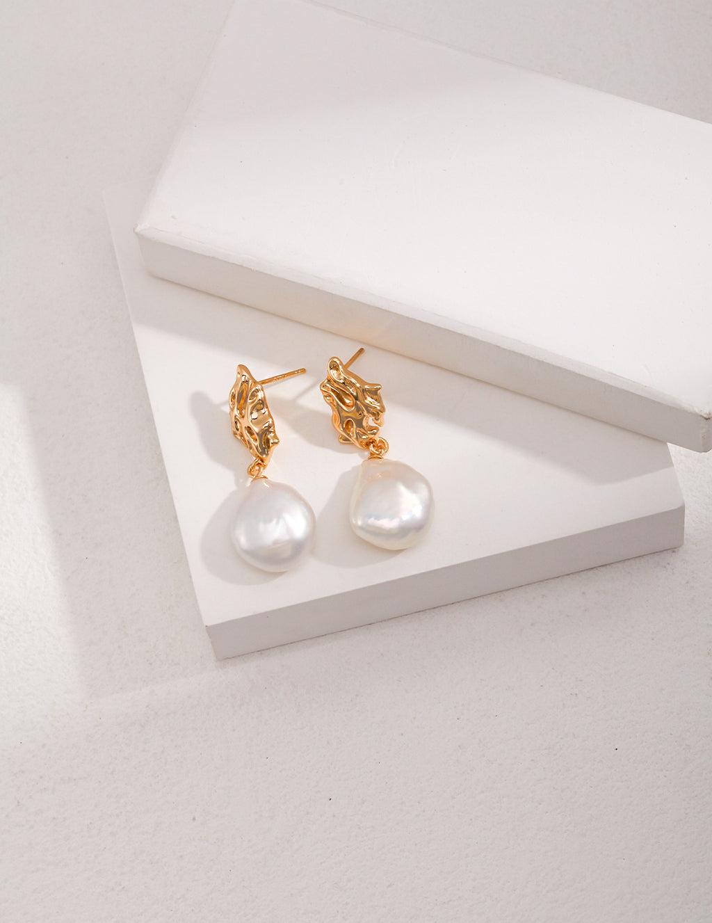 Vintage-gold sterling silver drop earrings with suspended natural baroque pearls.