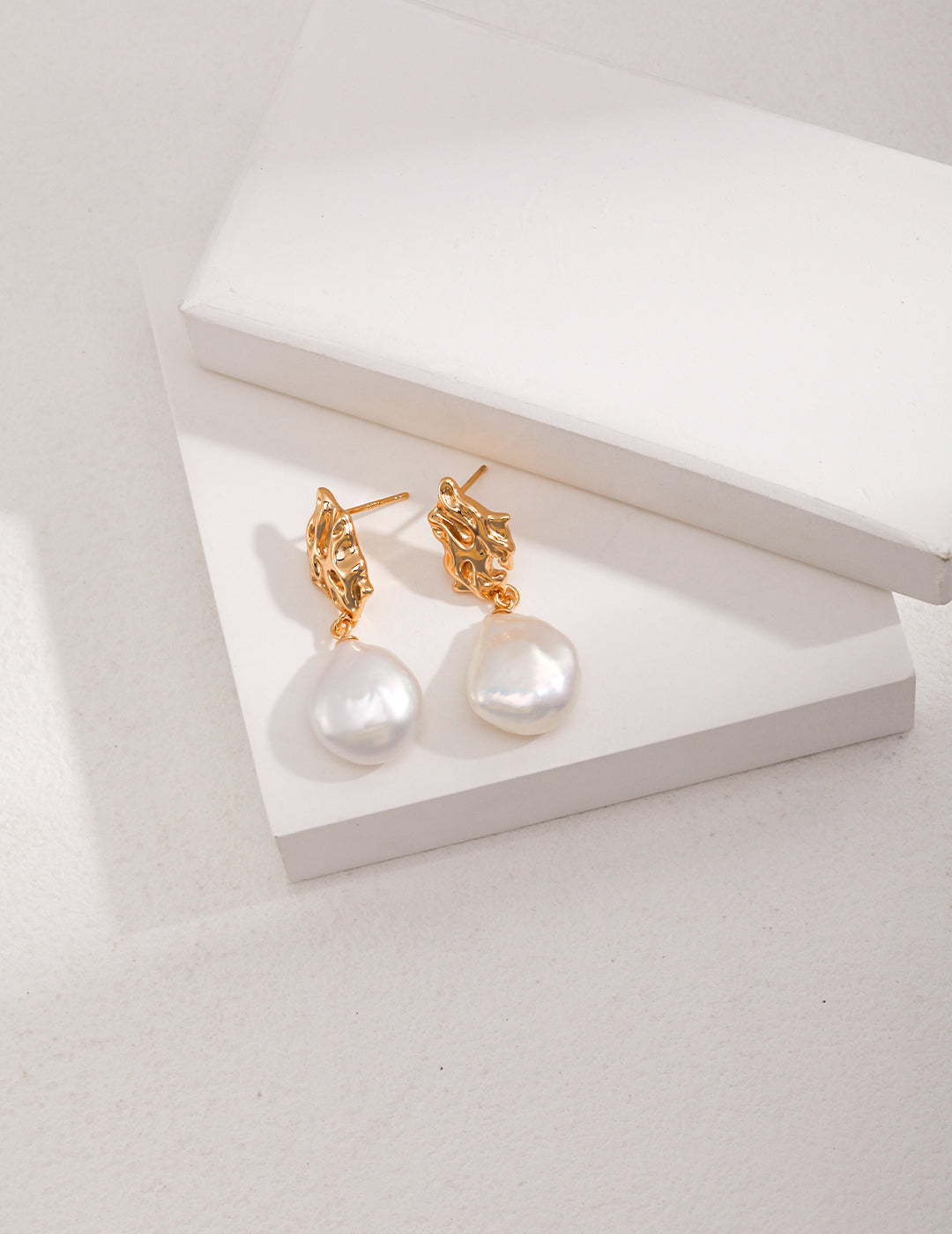 Vintage-gold sterling silver drop earrings with suspended natural baroque pearls.
