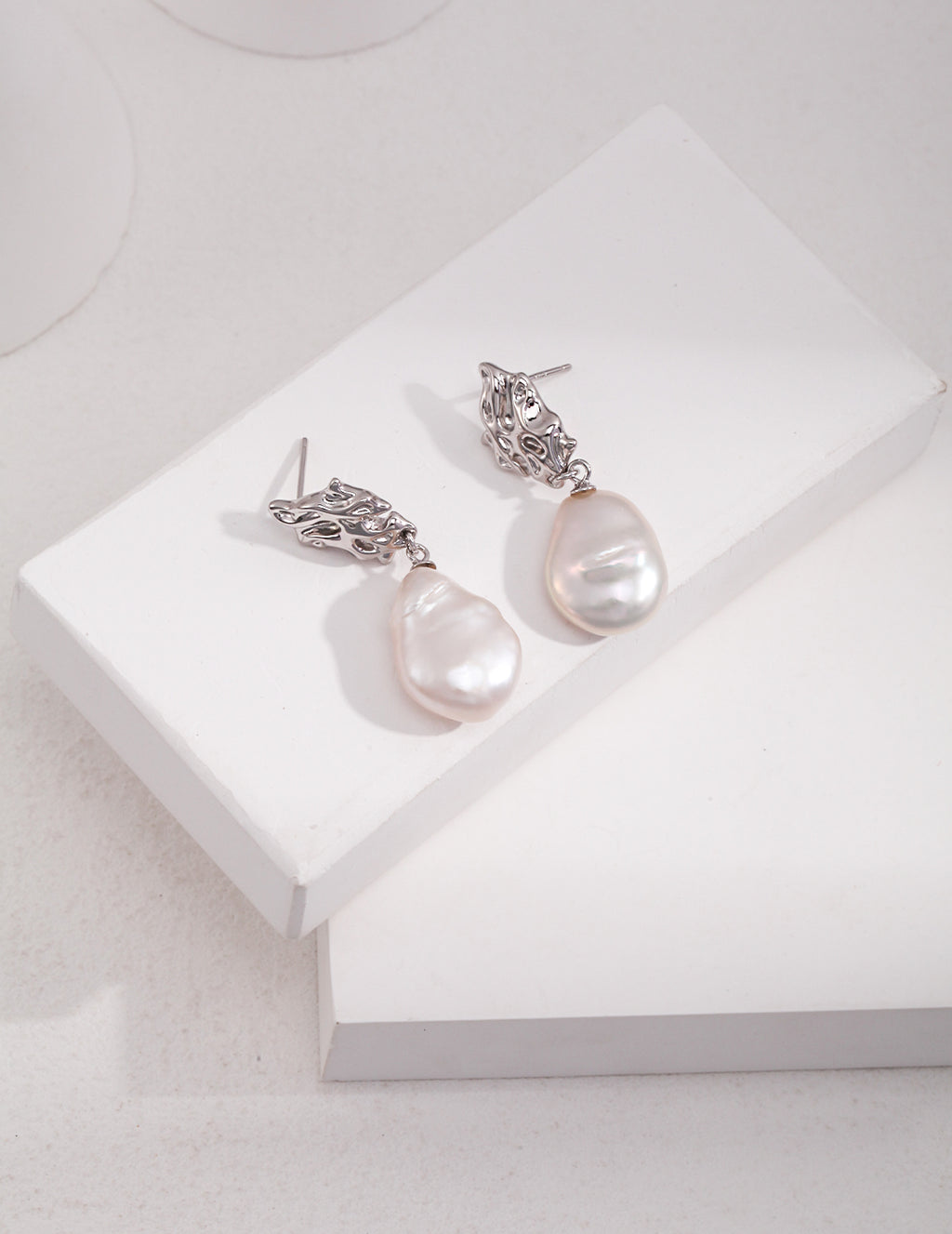 Vintage-gold sterling silver drop earrings with large irregular baroque pearls suspended beneath sculptural openwork metal studs.