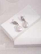 Vintage-gold sterling silver drop earrings with large irregular baroque pearls suspended beneath sculptural openwork metal studs.