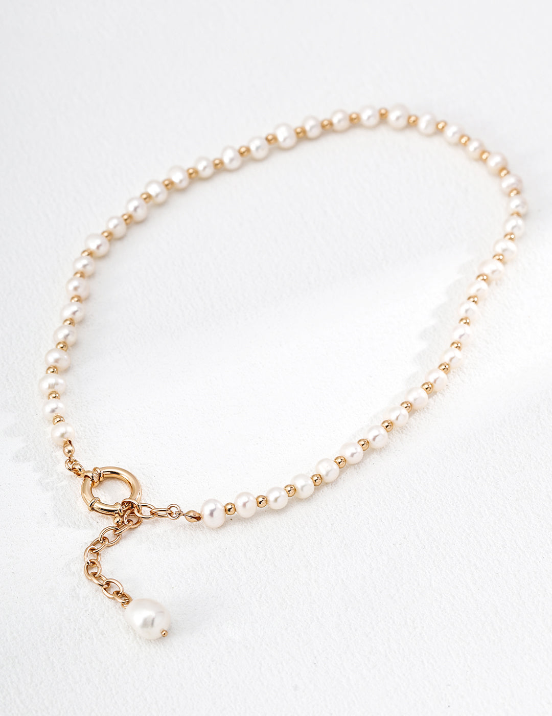Natural pearl necklace with vintage-gold beads, exposed circular clasp, extension chain and suspended baroque pearl.