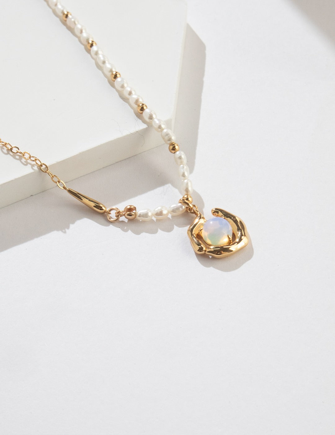Sterling silver necklace with opal and natural pearl details arranged along a delicate chain.