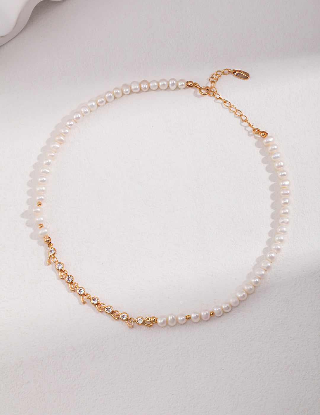 Vintage-gold sterling silver necklace with natural pearls and an off-center sequence of round clear stones in linked metal settings.