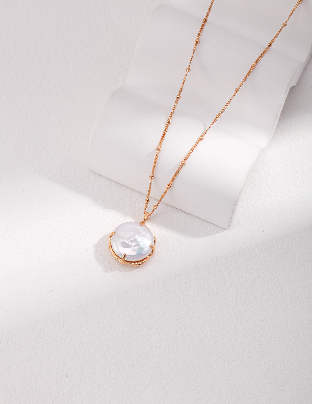 Vintage-gold sterling silver necklace with natural pearl details and a sculptural pendant composition.