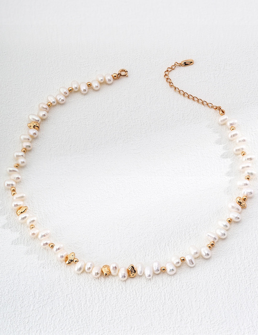Vintage-gold sterling silver necklace with irregular natural pearls, polished spherical beads and scattered sculptural metal accents.