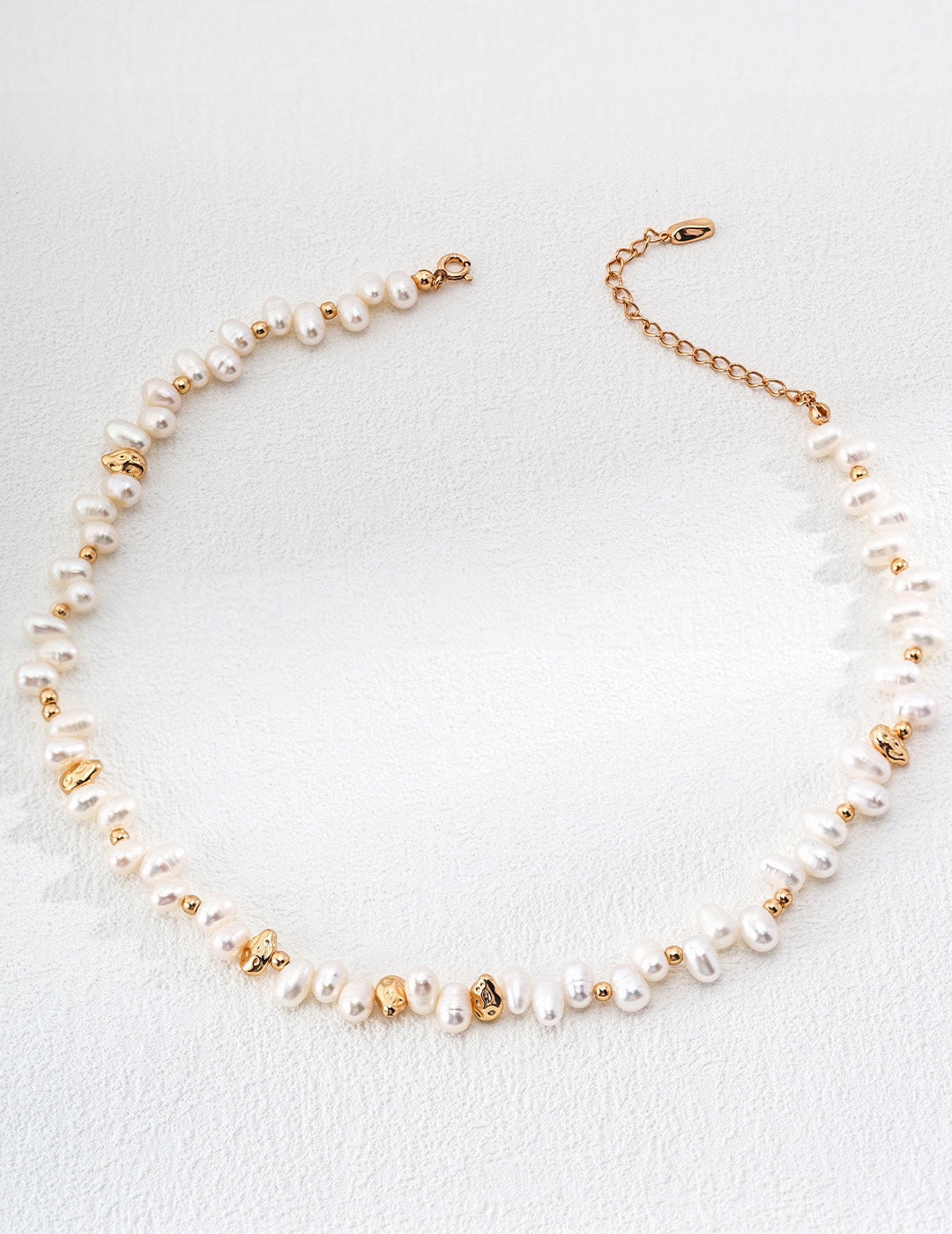 Vintage-gold sterling silver necklace with irregular natural pearls, polished spherical beads and scattered sculptural metal accents.