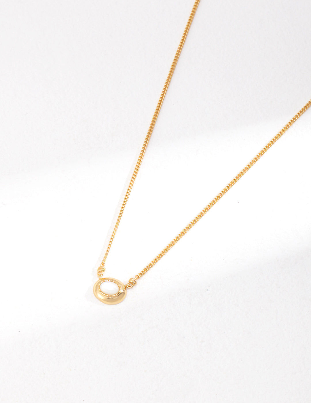 Vintage-gold sterling silver necklace with a small oval mother-of-pearl pendant in a softly irregular metal surround.